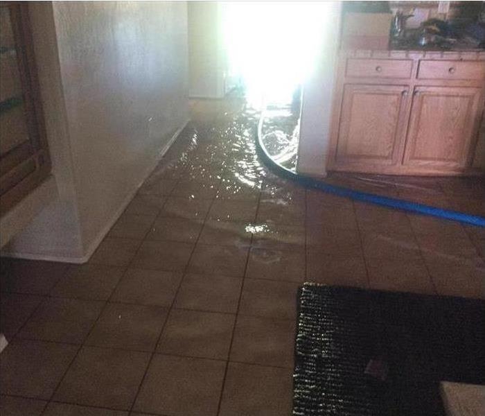 flooding on tile floor in kitchen and hallway, blue hose