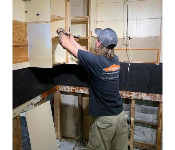 SERVPRO technician in the kitchen with removed cabinets
